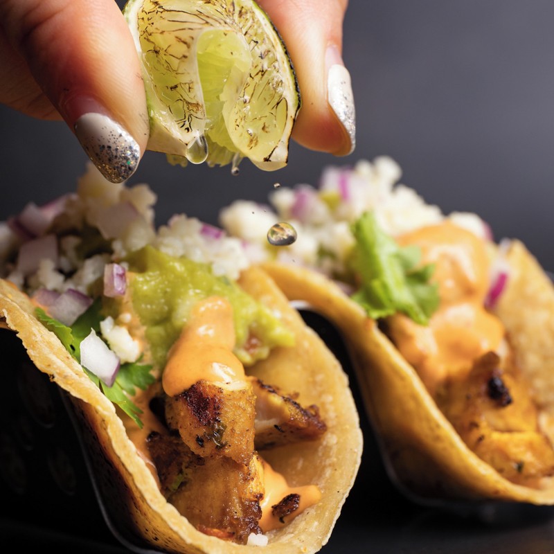 Hand squeezing lime on chicken taco