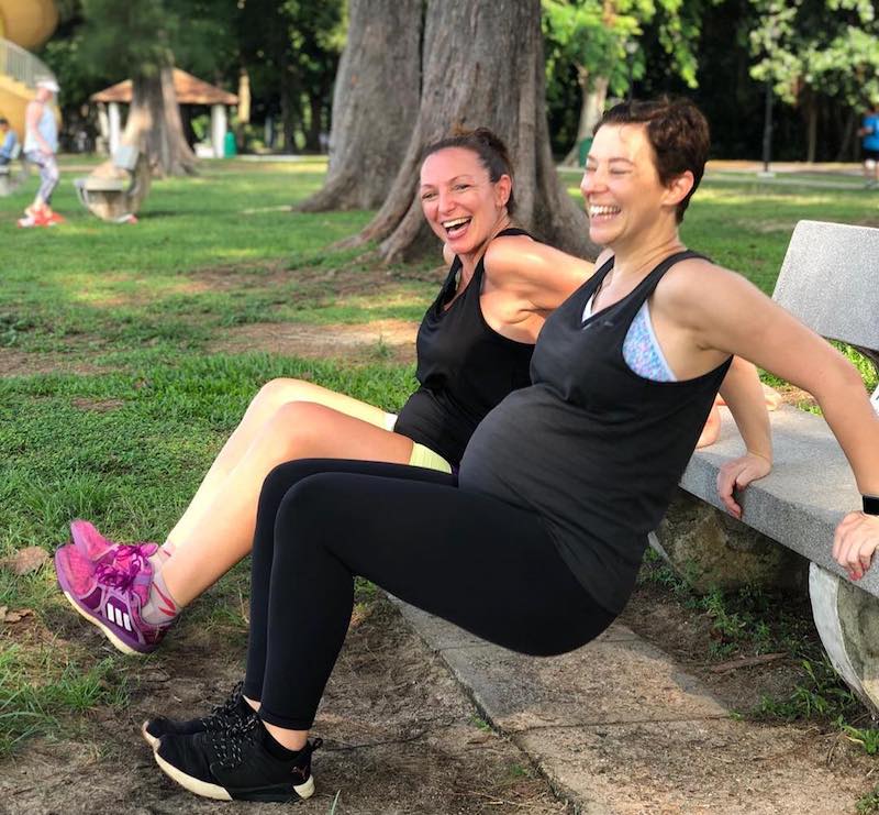 Two pregnant ladies doing tricep dips in the park