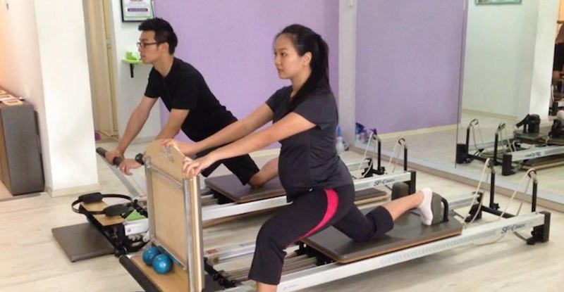 A pregnant lady and her partner doing prenatal pilates