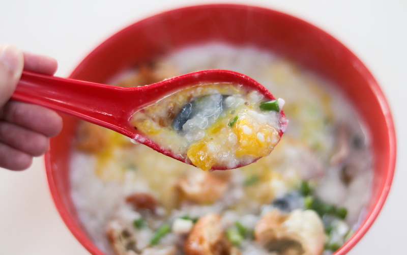 A spoonful of egg and century egg from the Large Pork Porridge With Egg and Century Egg porridge