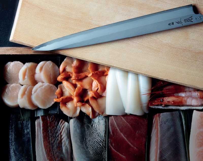 A array of sashimi with a wooden chopping board and Japanese knife