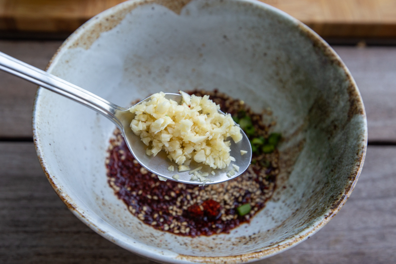 Spoon of minced garlic into bowl