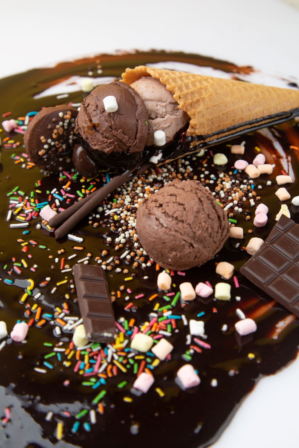 Chocolate ice cream cone lying in chocolate sauce