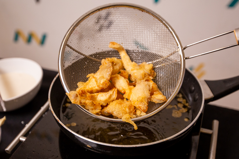 straining deep-fried tempura mushrooms
