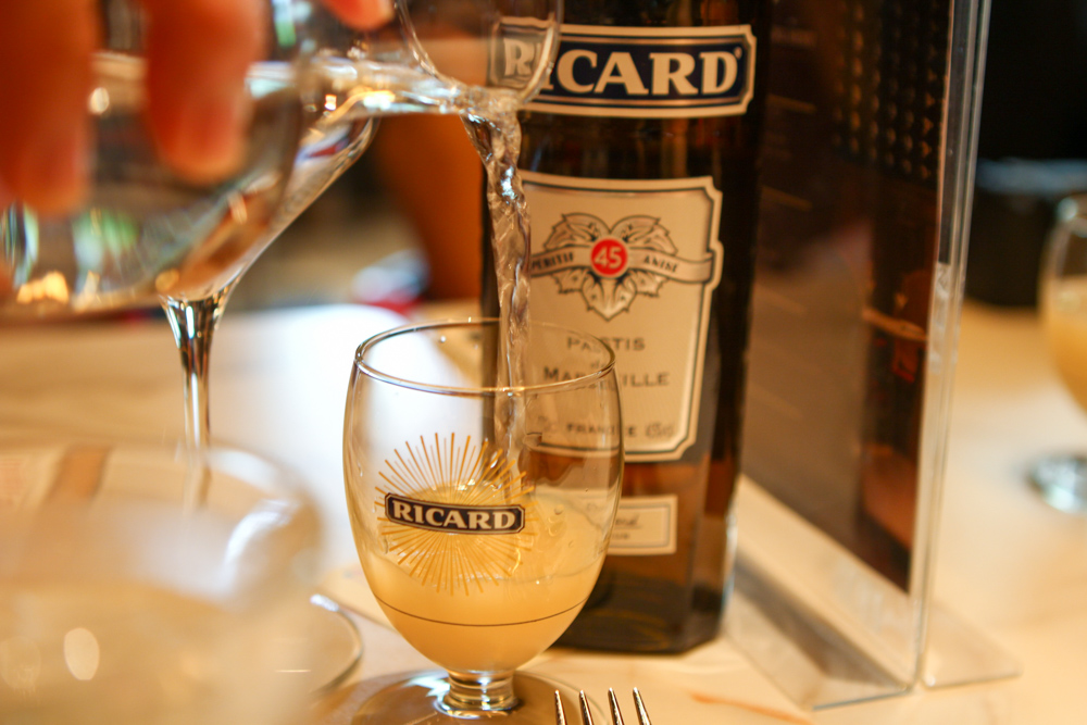 Image of server pouring water into a glass of Ricard pastis