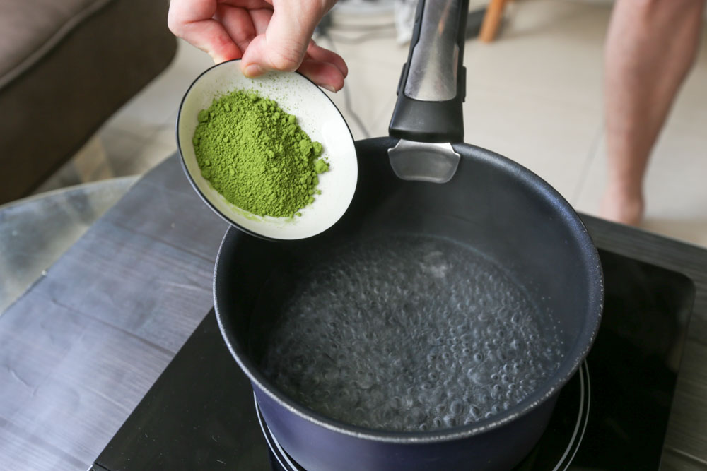 Photo of adding matcha powder to pot of boiling water