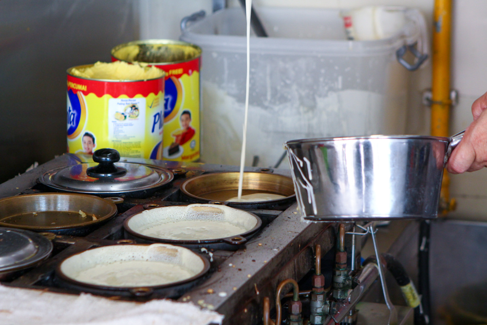 Close-up of stall owner preparing appam