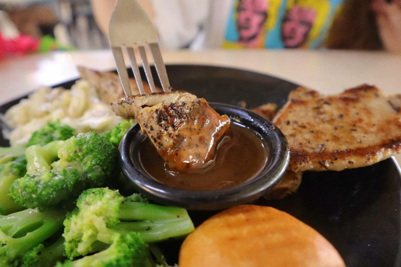 the flying pan - pork chop dipping in sauce