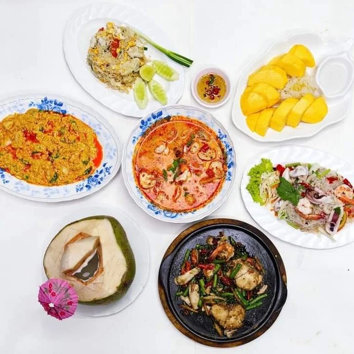 Lek Seafood - Food spread including mango sticky rice, tom yum goong, and fresh coconut 