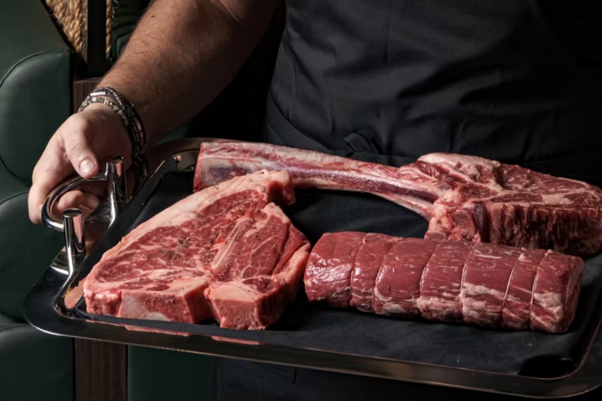 steak - man carrying raw steak on tray