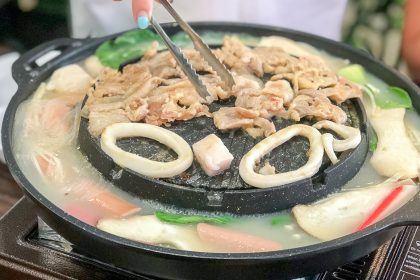 Pieces of pork being cooked on a full mookata grill